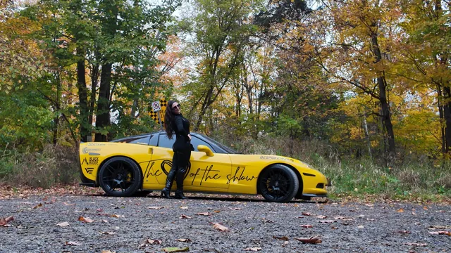 Chelsea leaning against the side of the Corvette.