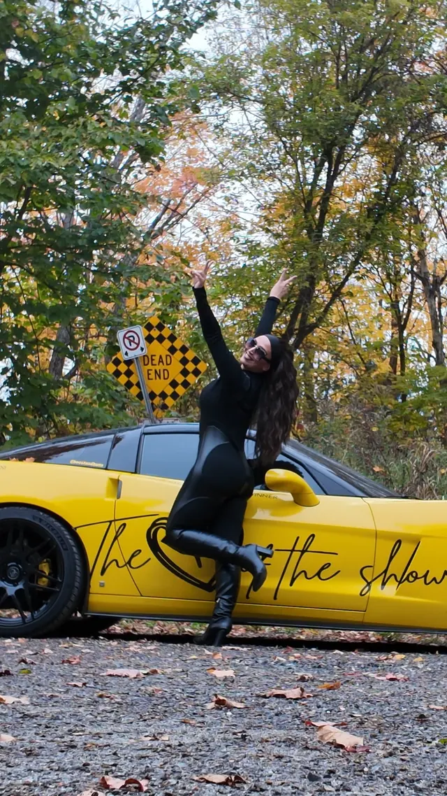 Chelsea reaching skyward beside the Corvette.