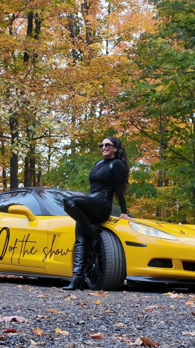 Chelsea smiling, seated on the Corvette's fender.
