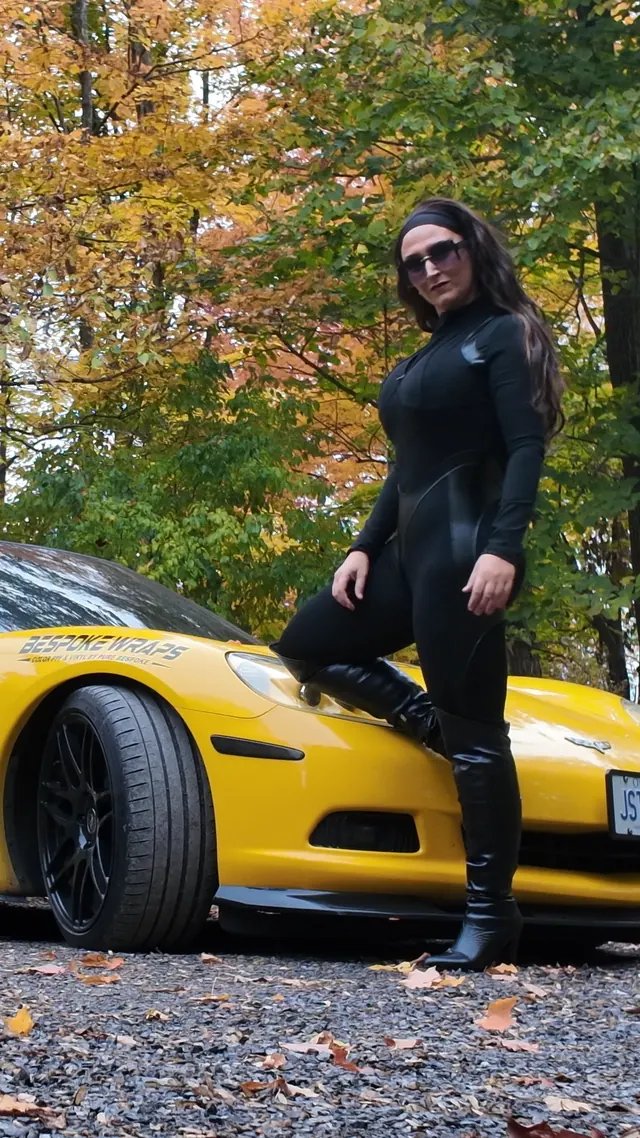 Chelsea standing with one boot on the Corvette's front wheel.